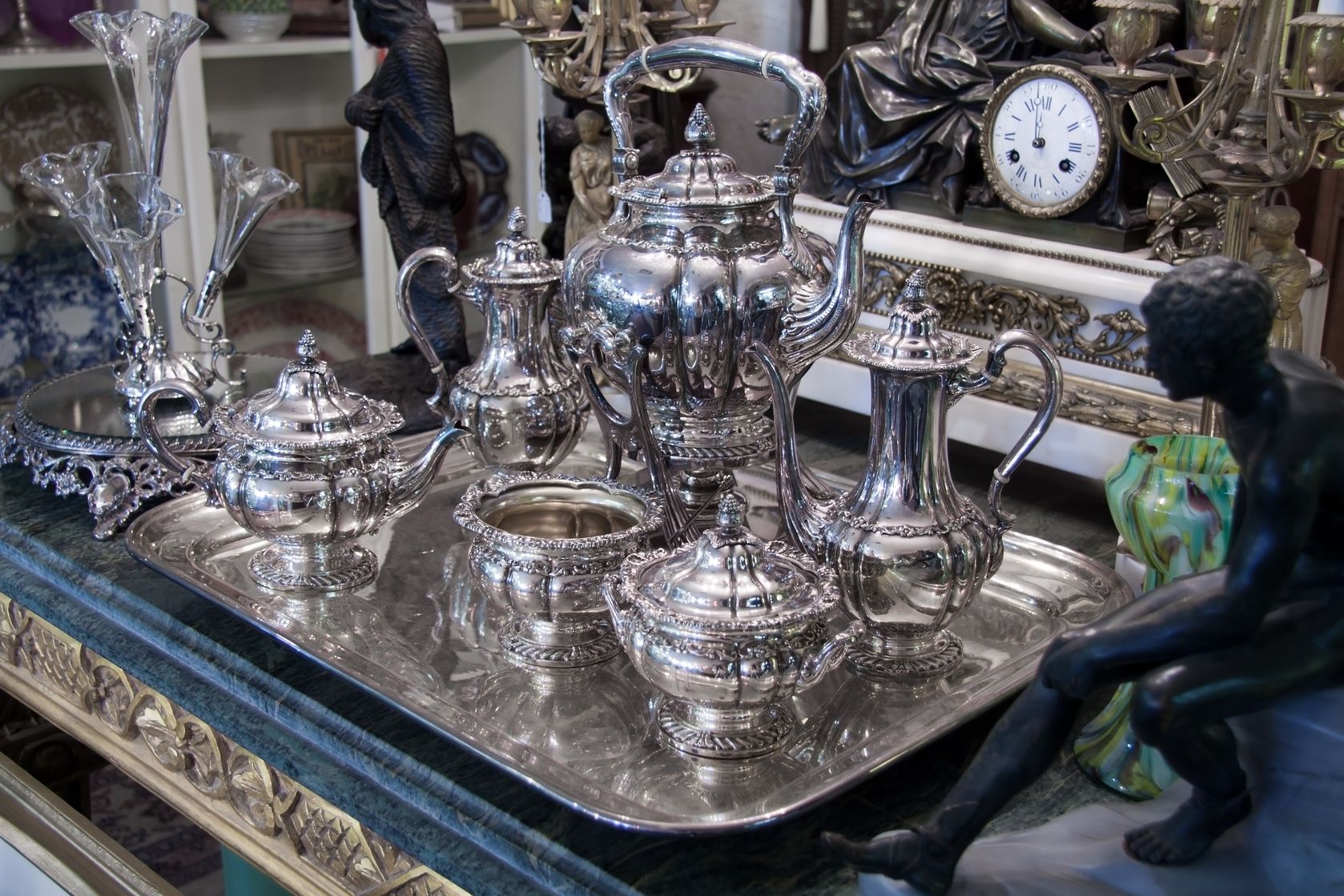 A silver tray with a variety of silver serving pieces on a table...